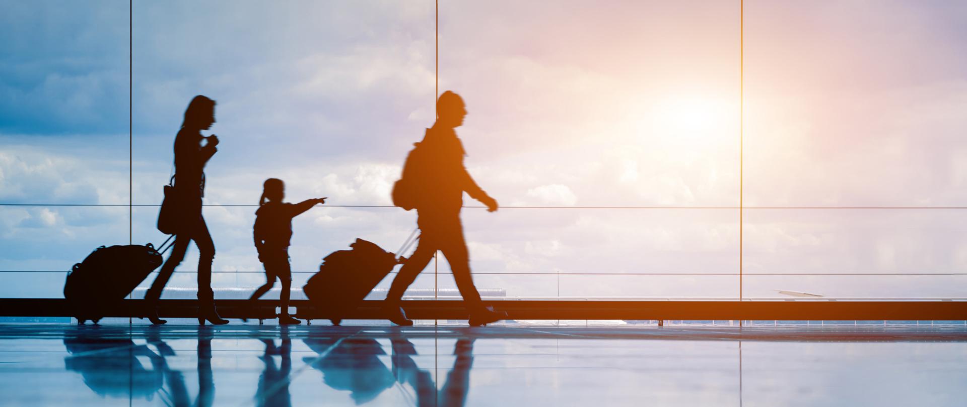 Turyści z walizkami maszerują po lotnisku