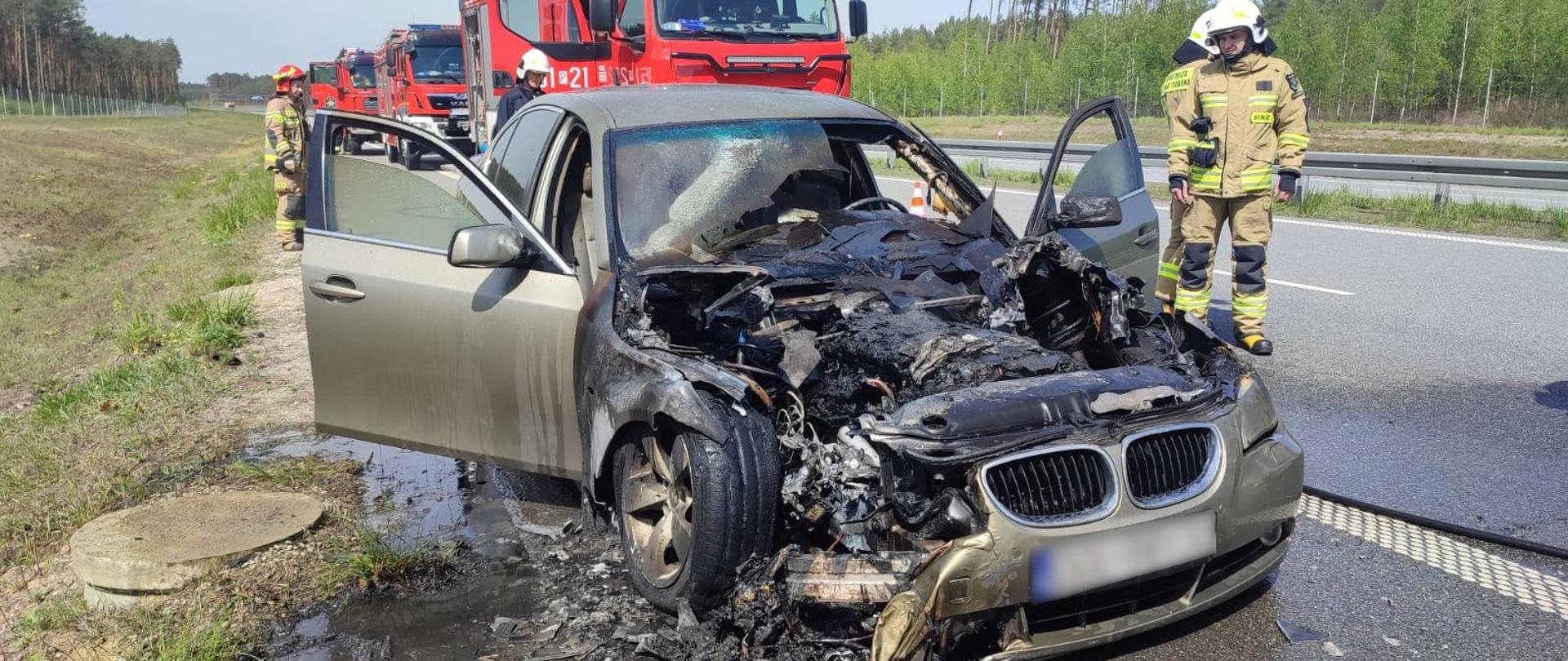 widoczne miejsce zdarzenia oraz uszkodzony pojazd po pożarze.