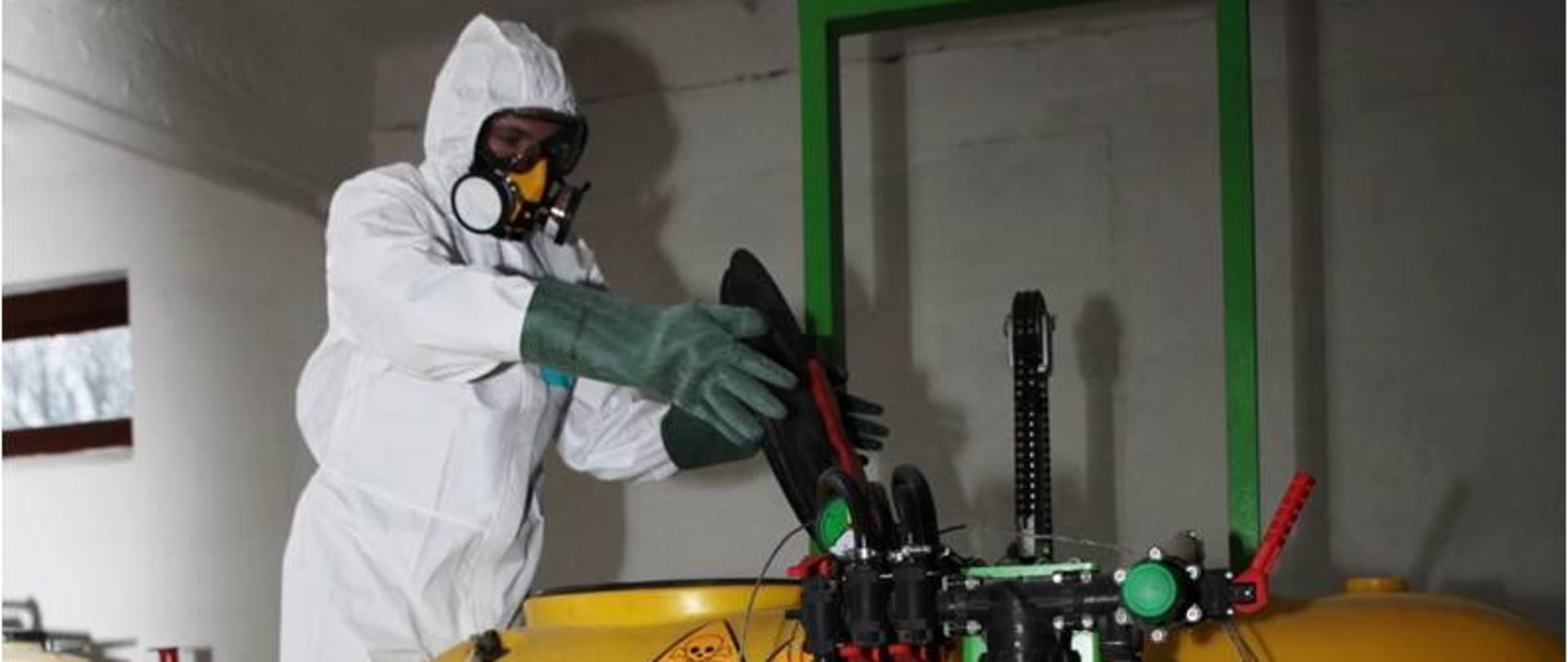 Uczeń w stroju ochronnym podczas pracy przy opryskiwaczu 