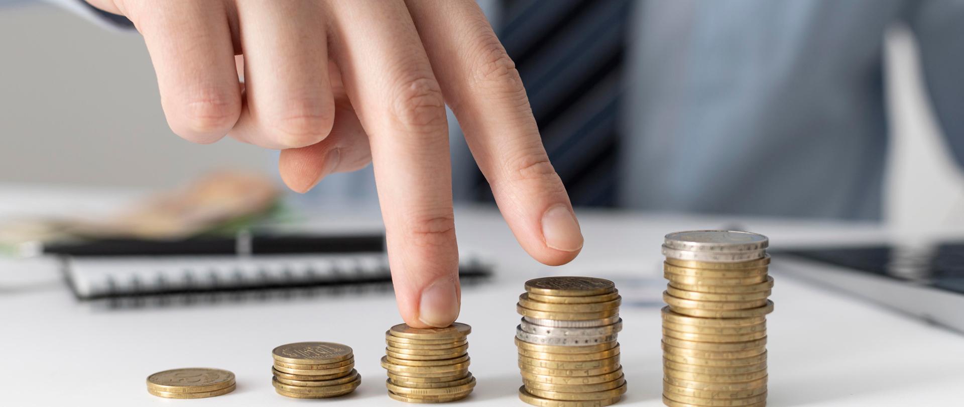 Na zdjęciu znajduje się pięć słupków monet składających się z kilku lub kilkunastu monet w słupku, ułożonych w kolejności rosnącej 