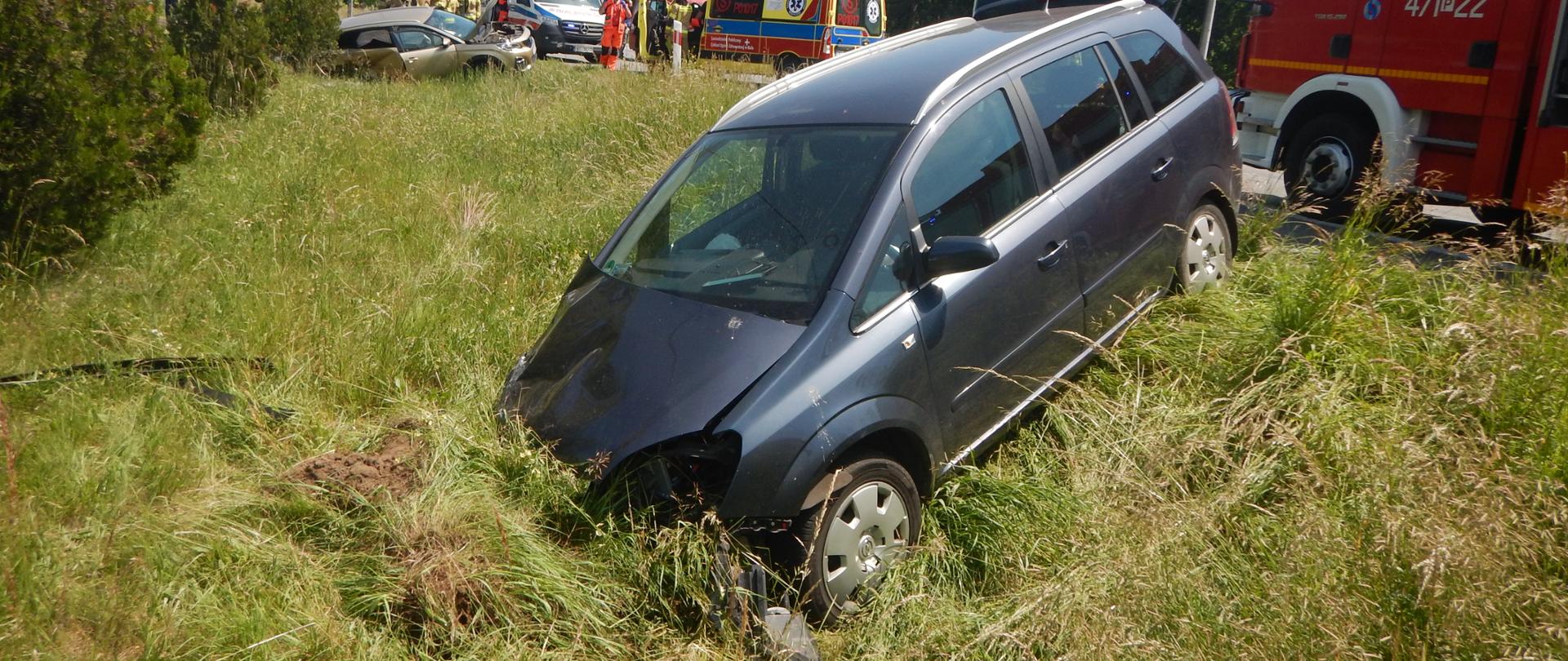 Zdjęcie przedstawia dwa rozbite samochody osobowe w przydrożnym rowie