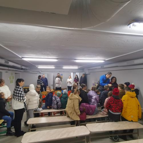 Grupa dorosłych i dzieci w schronie 