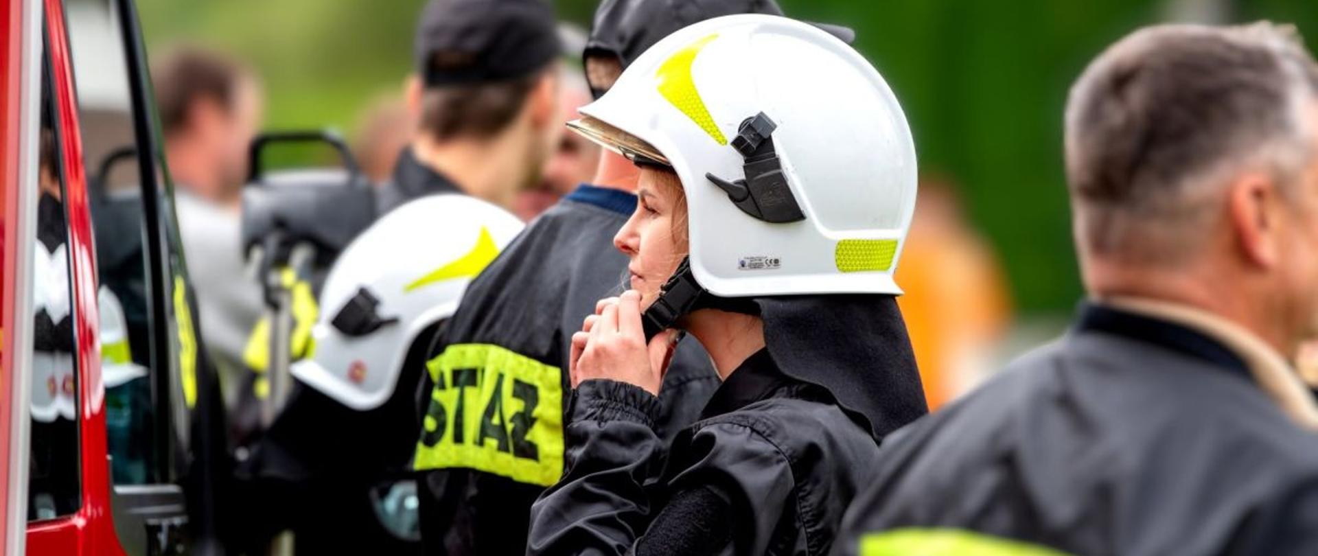 Zdjęcie przedstawia druhnę OSP która zapina hełm.