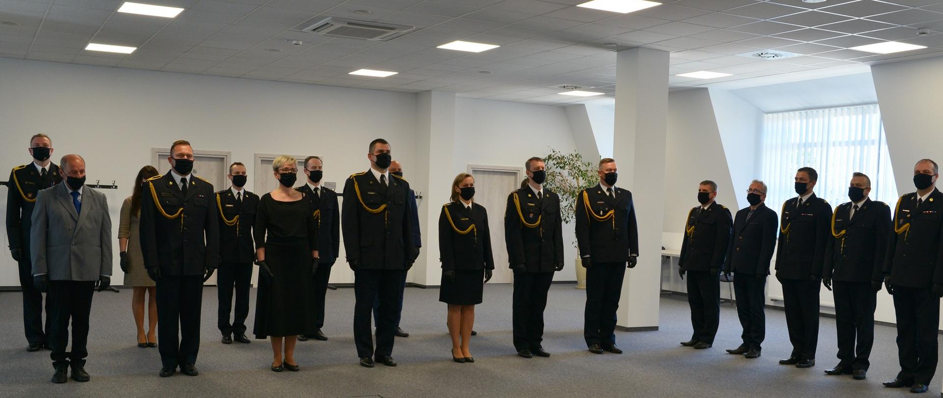 Strażacy, korpus służby cywilnej stoją podczas uroczystego apelu. 