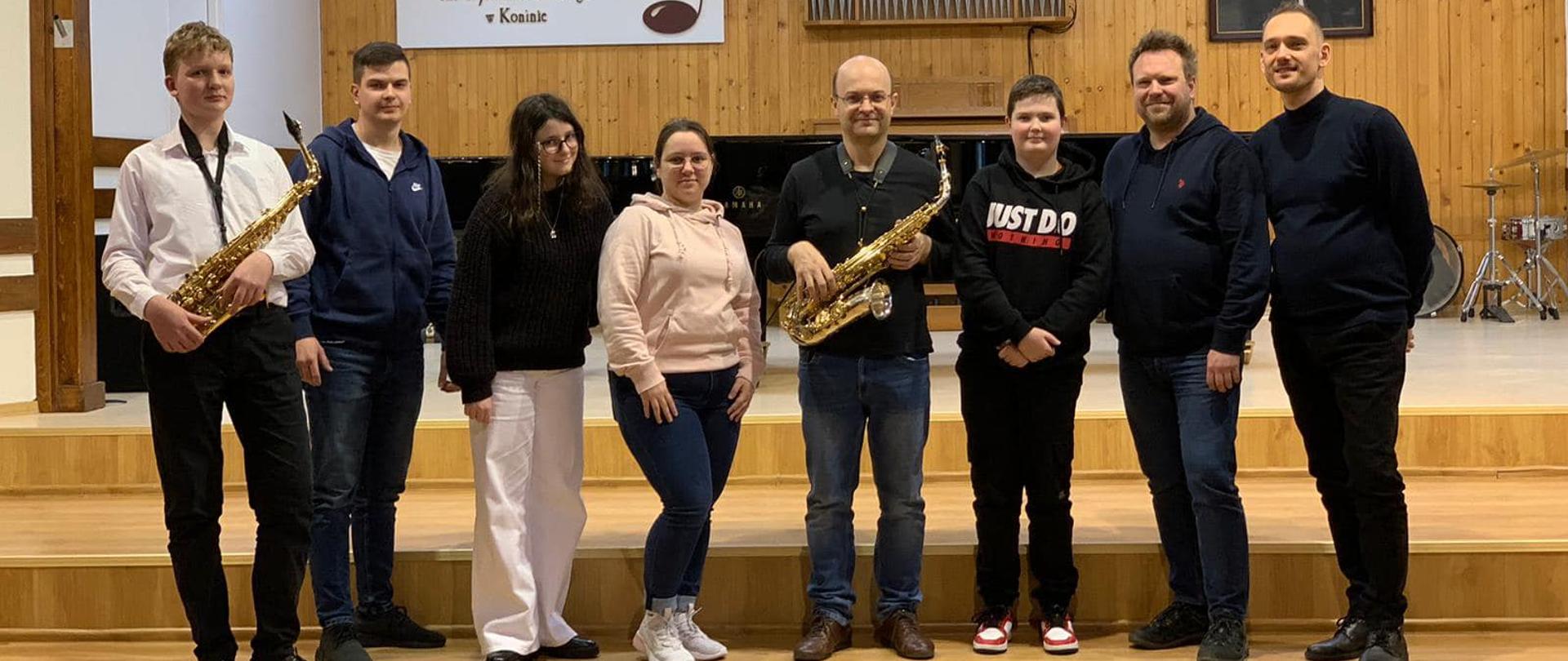Uczesnicy stoją na scenie PSM w Koninie, w środku prowadzący.