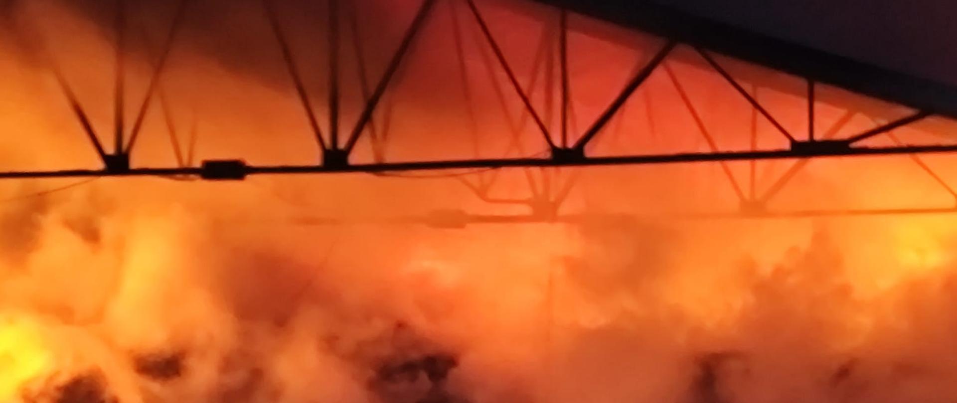 Zdjęcie przedstawia wiatę, gdzie trwa pożar zgromadzonych odpadów.