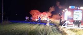 Na zdjęciu widoczny w oddali pożar drewnianego barakowozu oraz kilku strażaków. Na pierwszym planie samochód gaśniczy z sochaczewskiej jednostki.