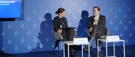 Na zdjęciu widać dwie osoby siedzące na scenie w tym wiceminister funduszy i polityki regionalnej Jan Szyszko w trakcie dyskusji