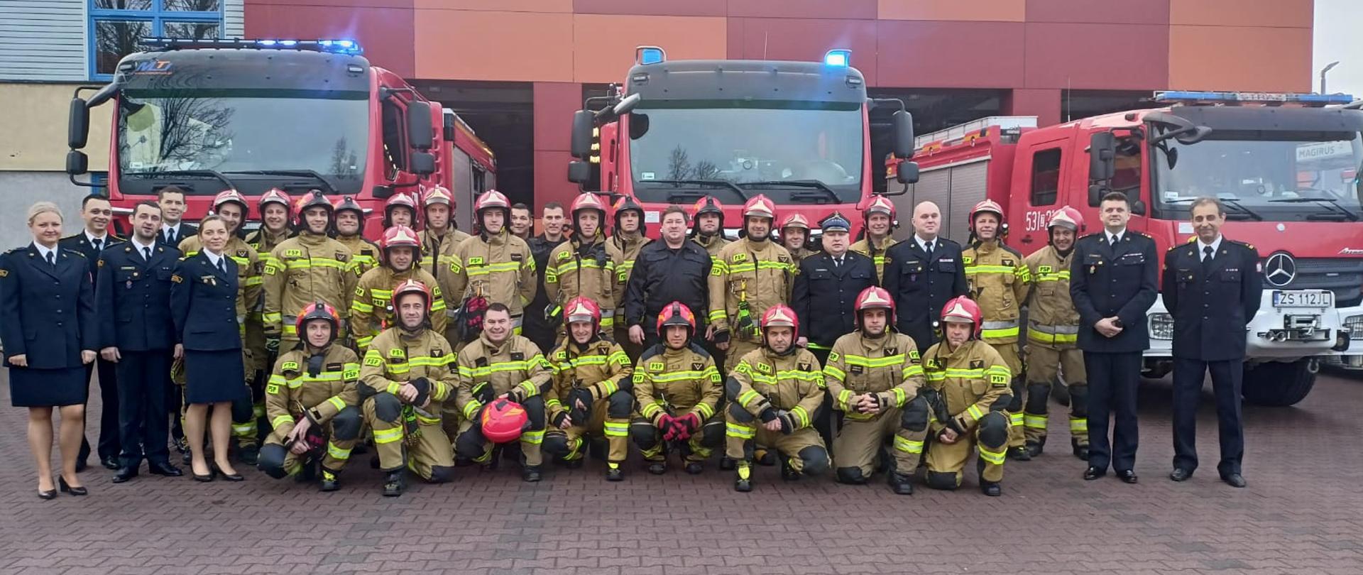 Zdjęcie grupowe z emerytem na tle samochodów pożarniczych
