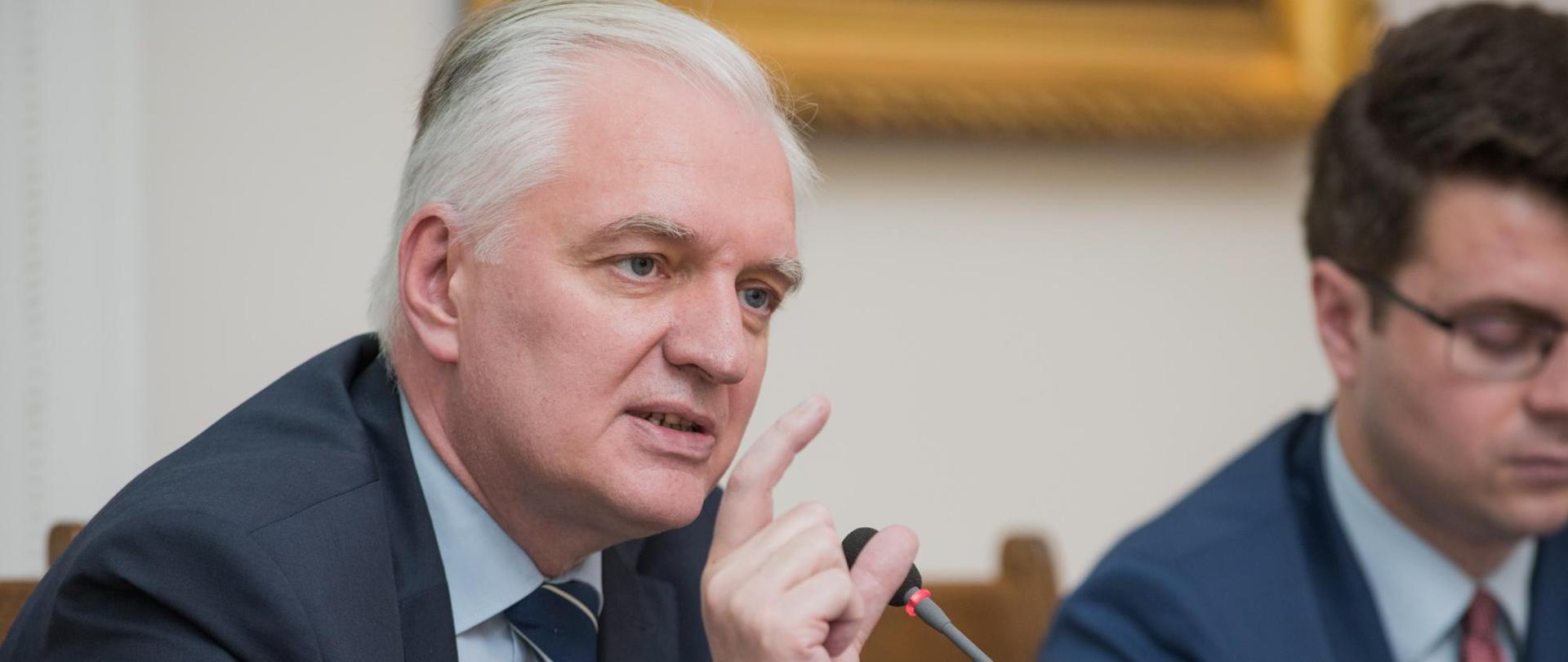 Minister Gowin mówi do mikrofonu, za nim Piotr Müller