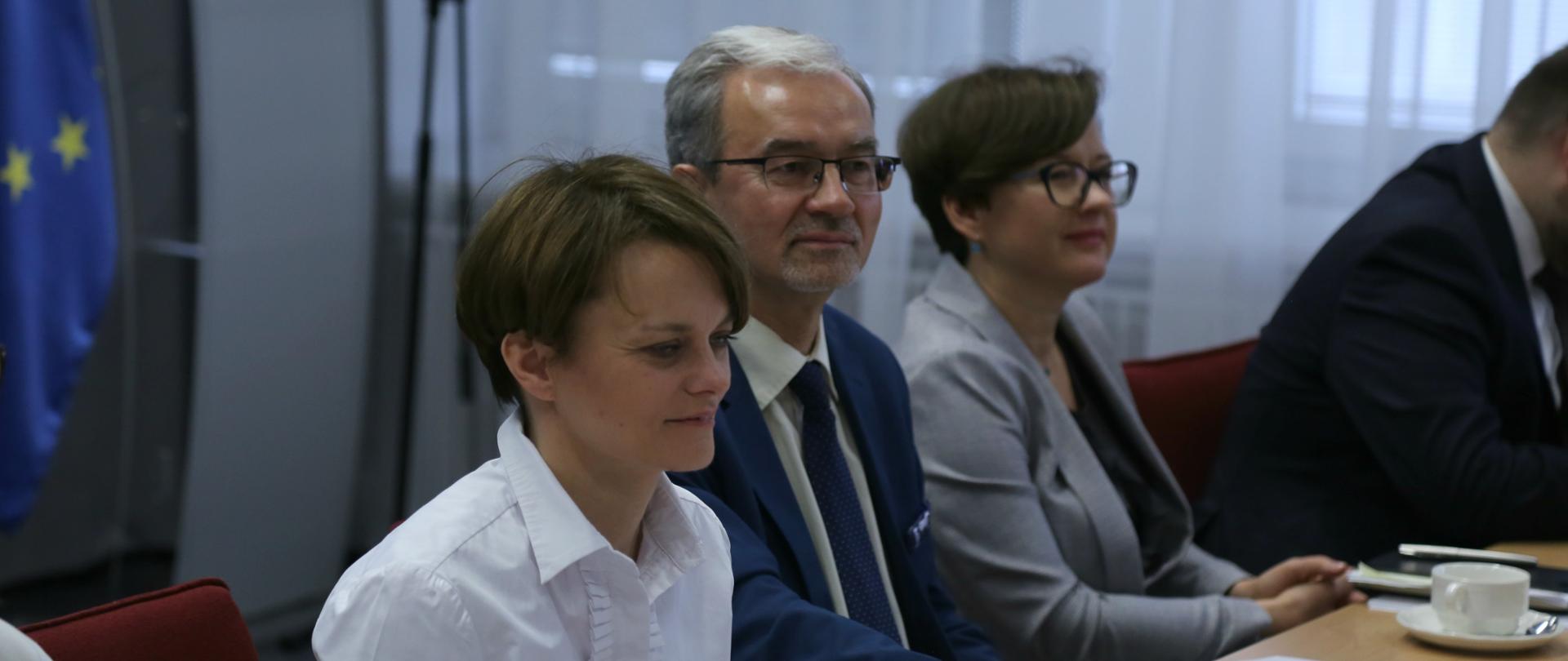 Trzy osoby przy stole prezydialnym w sali konferencyjnej, pierwsza od lewej minister Jadwiga Emilewicz, w środku minister Jerzy Kwieciński, z prawej dyrektor Małgorzata Szczepańska.