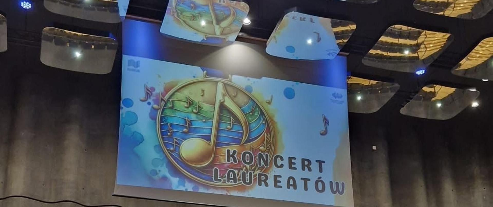 Fortepian stoi na scenie, nad sceną na rzutniku napis Koncert Laureatów.