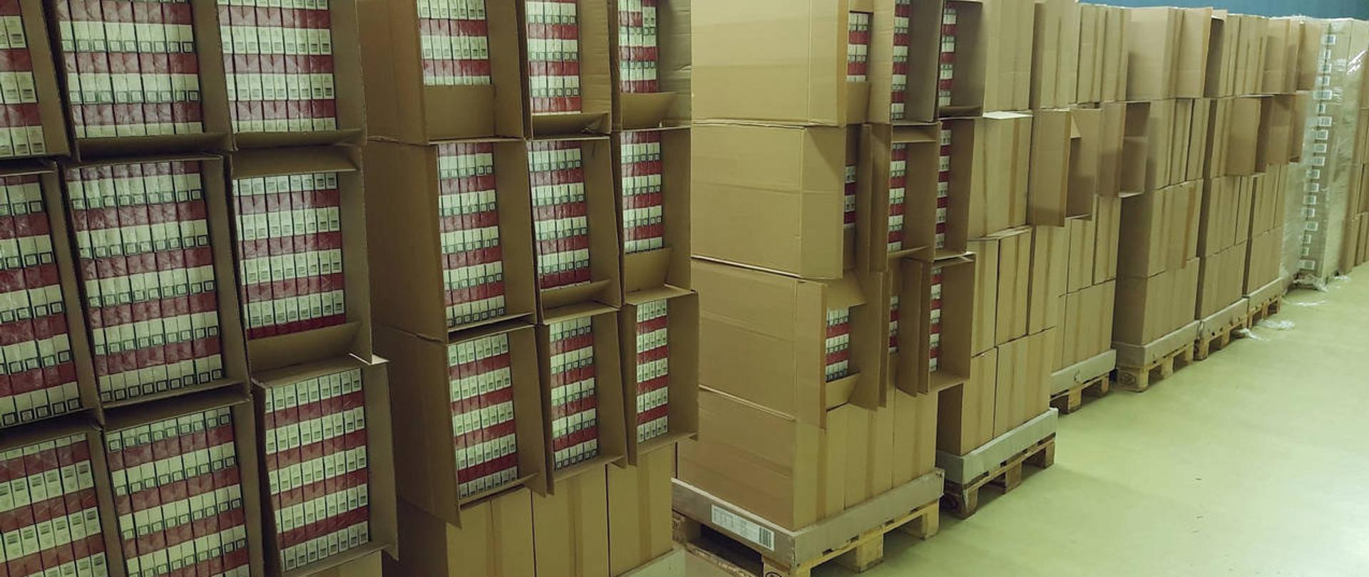Magazyn z nielegalnymi papierosami w kartonach ułożonych na paletach.