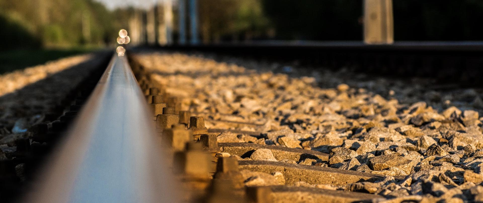szyna kolejowa w dużym przybliżeniu, w oddali światło