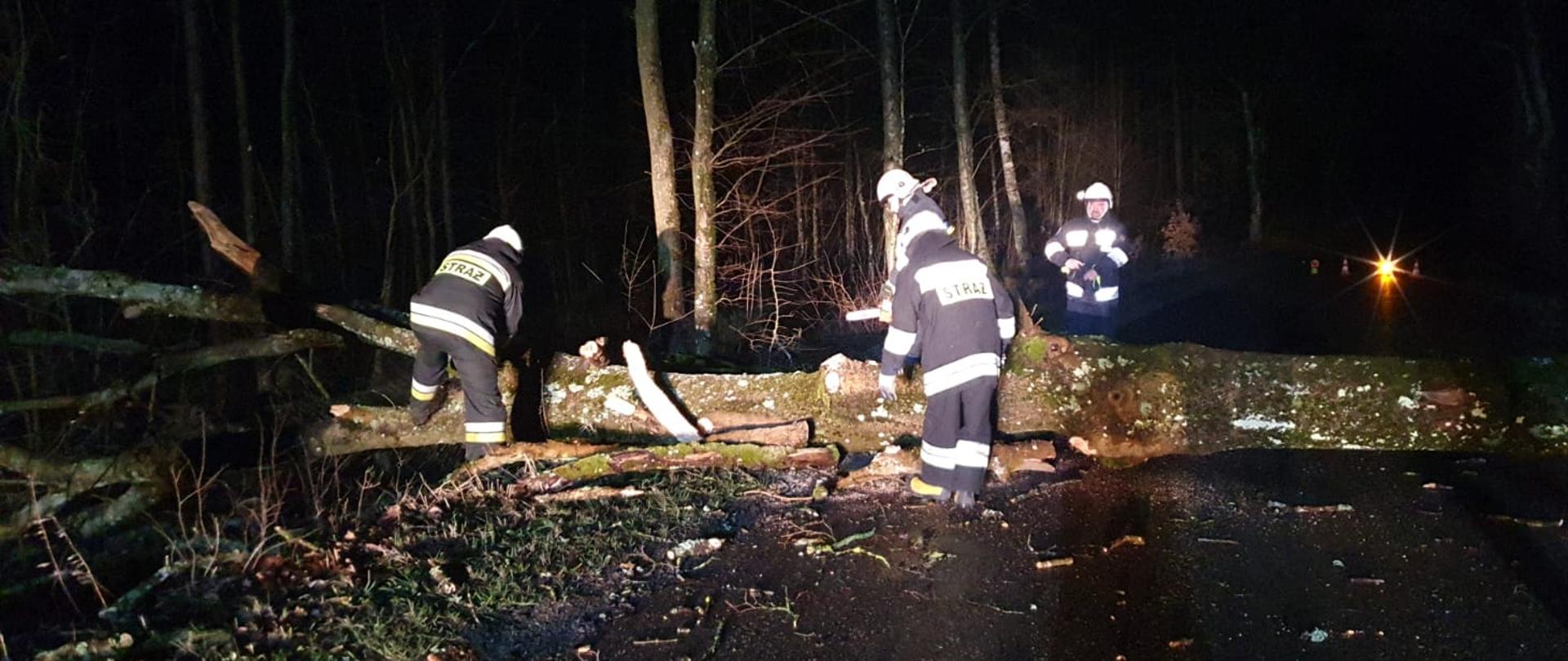Strażacy usuwający z drogi powalone drzewo