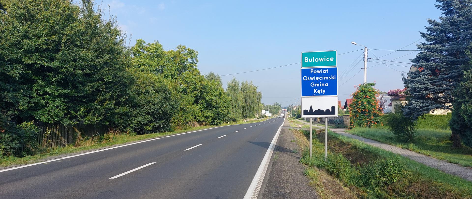 DK52 w Bulowicach, przy drodze znak z nazwą miejscowości, w oddali zabudowania