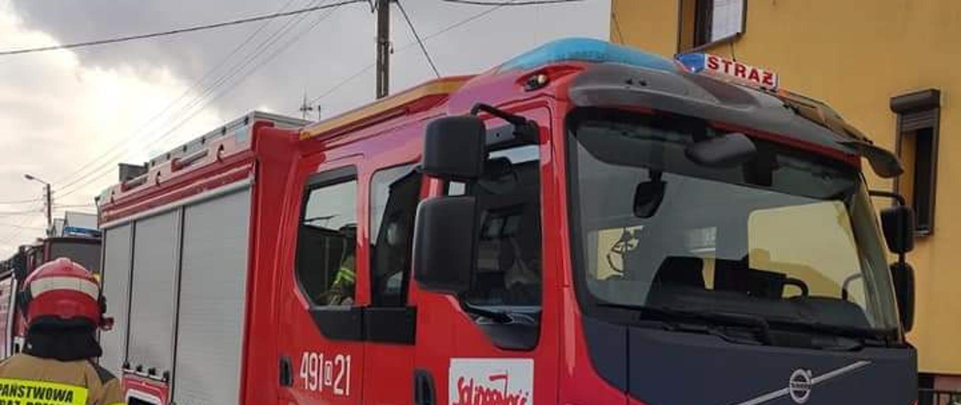 Na zdjęciu znajduje się samochód pożarniczy stojący przy budynku