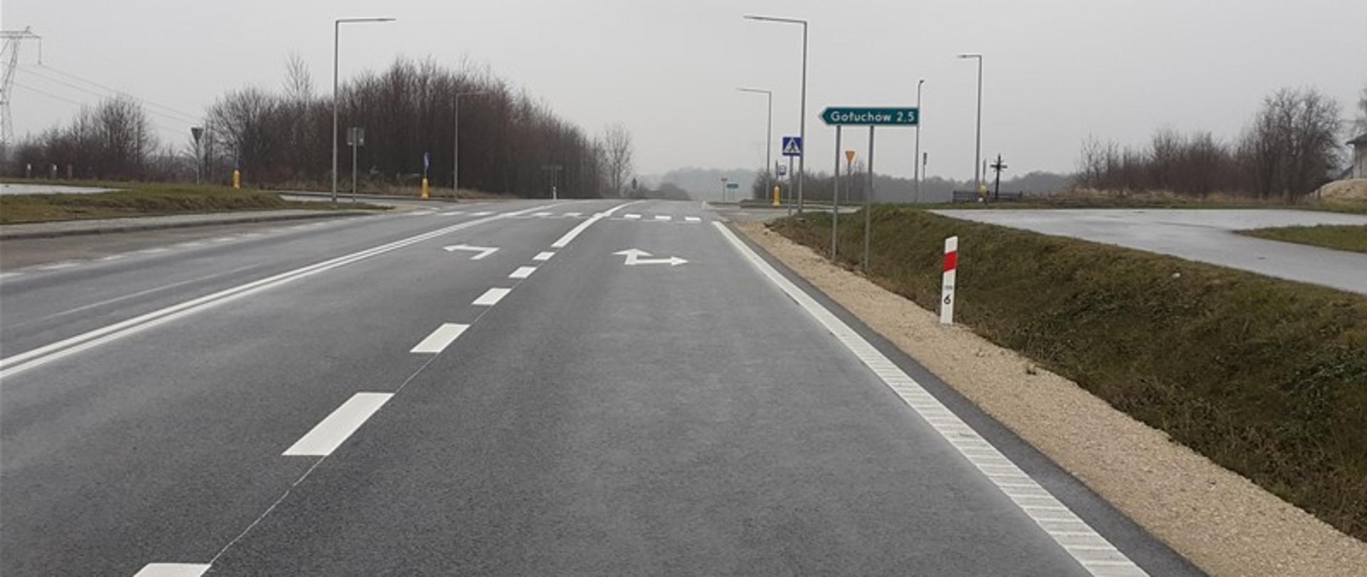DK78 odcinek Kije - Chmielnik - asfaltowa droga jednojezdniowa, na niej namalowane białe linie przerywane i strzałki, w oddali skrzyżowanie z przejściem dla pieszych, drogowskaz, Wzdłuż drogi trawa, krzewy rowy