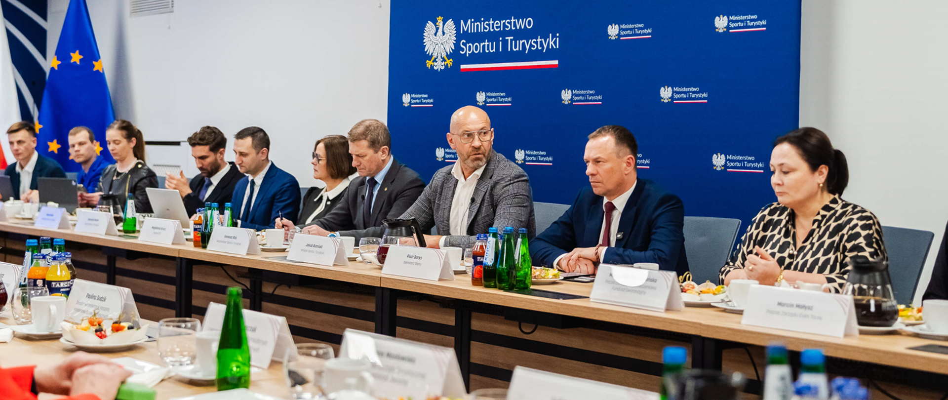 spotkanie w ministerstwie sportu i turystyki po ewakuacji turystów z Bliskiego Wschodu. Ministrowie siedzą za stołem na tle niebieskiej ścianki z logiem ministerstwa