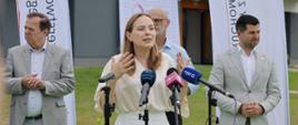 Minister funduszy i polityki regionalnej Katarzyna Pełczyńska-Nałęcz stoi i przemawia do mikrofonów, po jej lewej stronie stoi prezes KZN Łukasz Bałajewicz