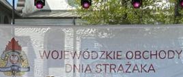Scena na placu kościuski w poddębicach, zastępca komendanta głównego PSP wręcza odznaczenia strażakom OSP oraz PSP wszyscy ubrani w mundury galowe