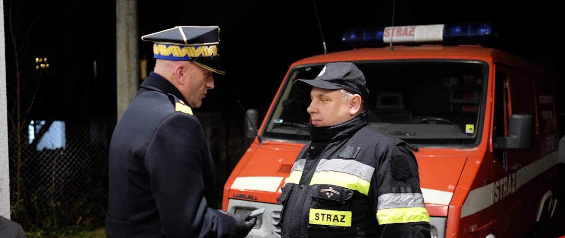 Zachodniopomorski Komendant wręcza kluczyki na ręce Naczelnika OSP Marianowo, w tle przekazywane samochody