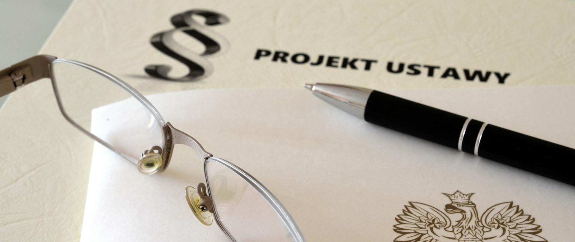 Okulary, długopis, projekt ustawy.