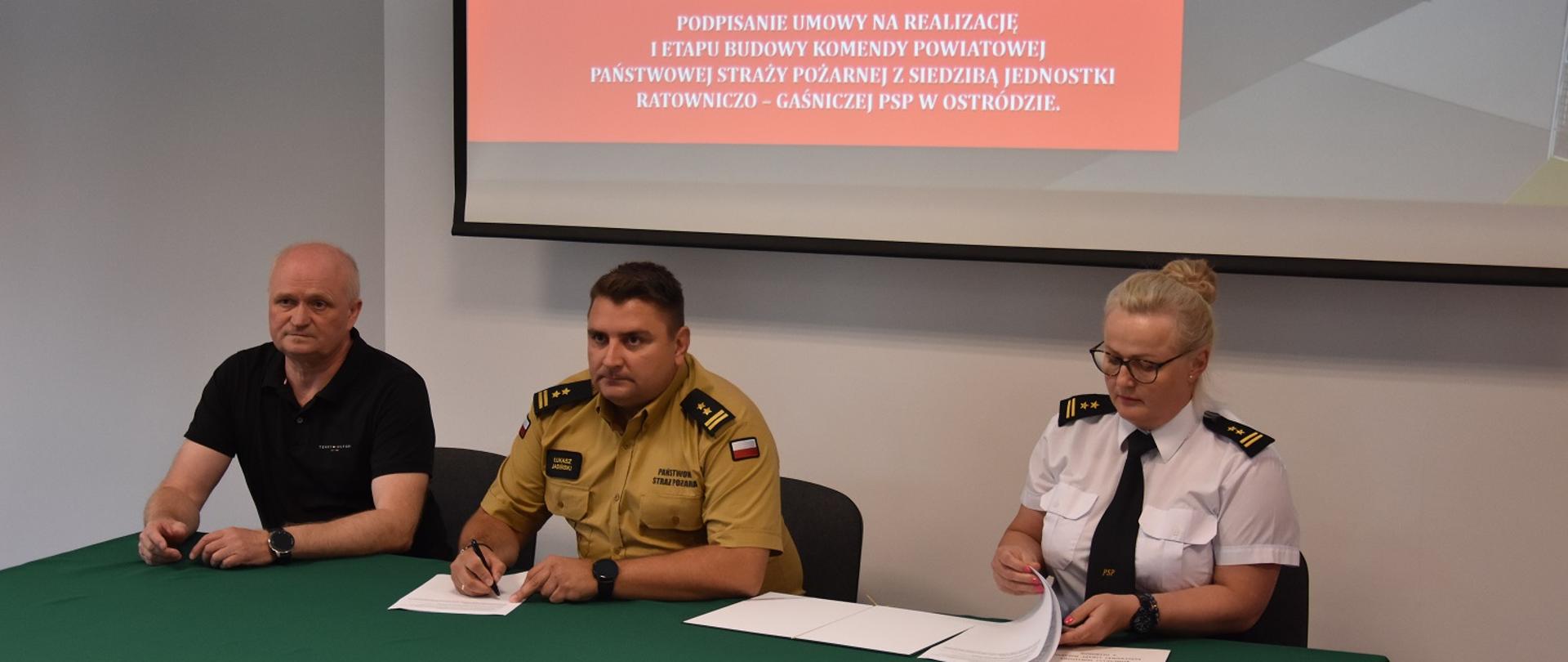 bryg. Łukasz Jasiński podpisuje umowę na realizację I etapu budowy nowej siedziby KP PSP w Ostródzie, po prawej stronie siedzi Mariusz Kortas członek zarządu firmy realizującej zadanie