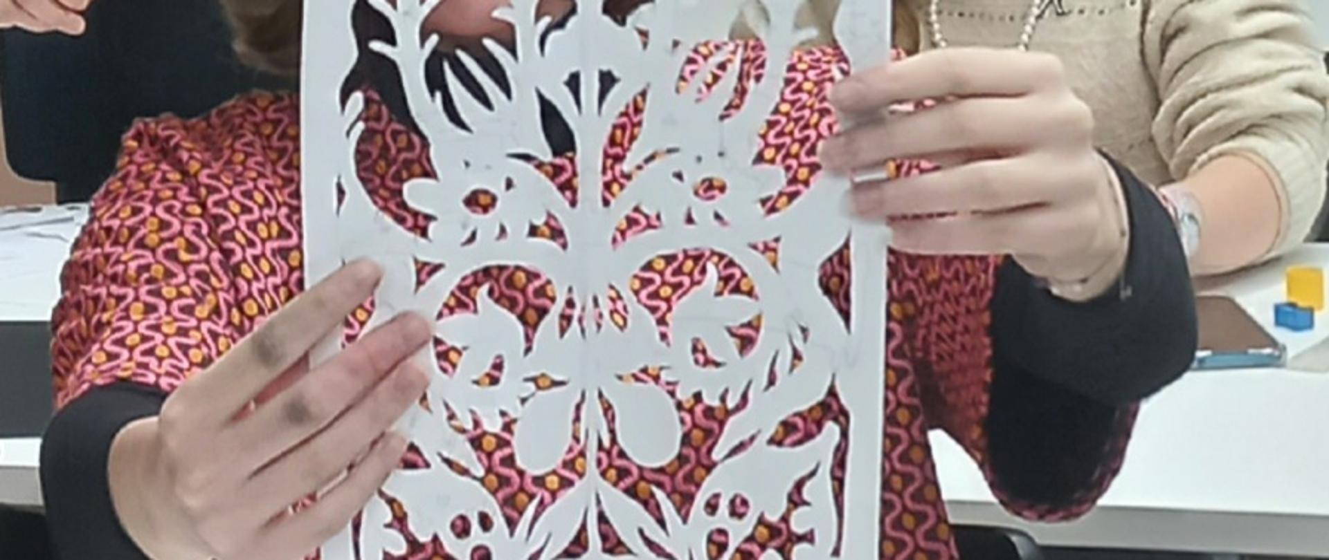 Na zdjęciu uczennica prezentuje swoją wycinankę z papieru