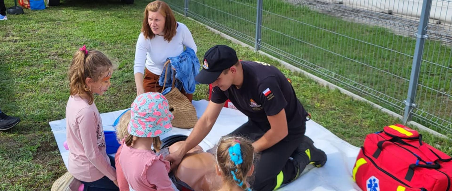 Strażak demonstruje pierwszą pomoc na manekinie dziecią i osobie dorosłej.