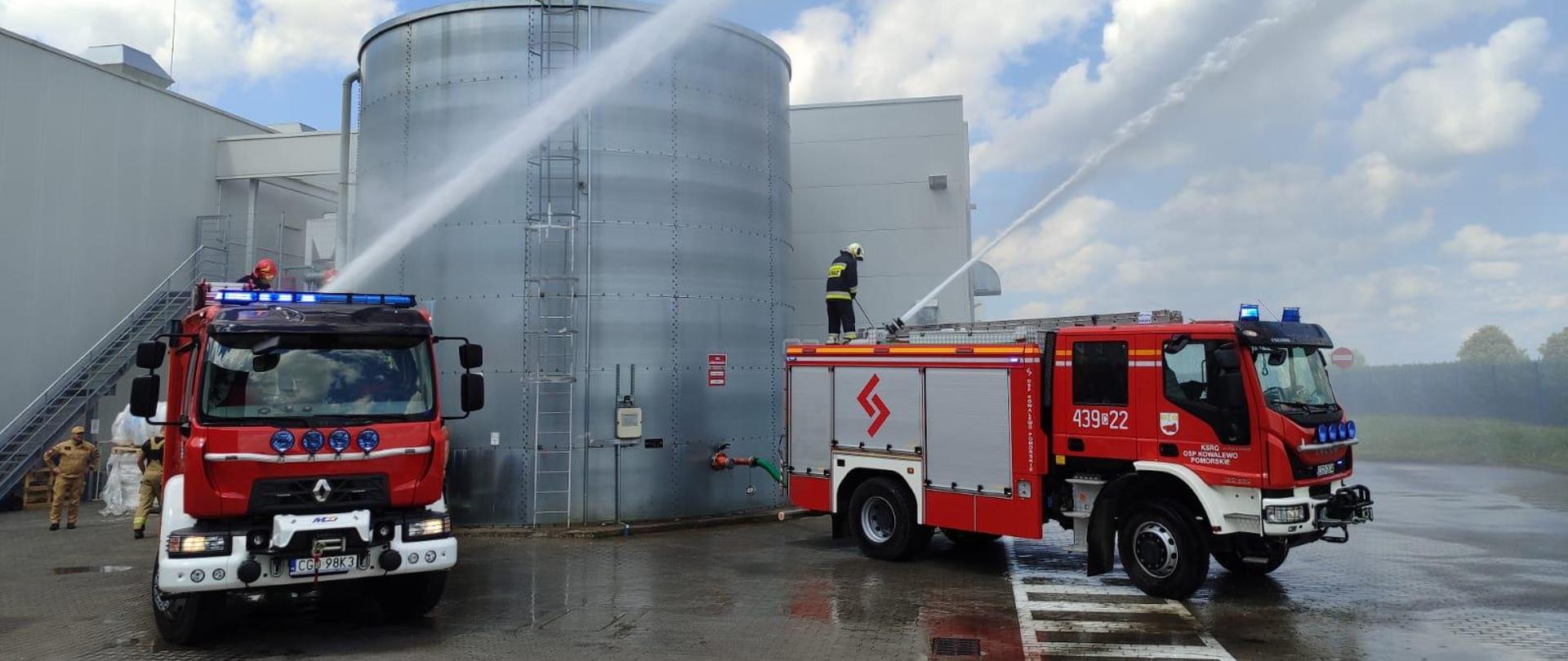 Strażacy podają wodę z działek wodno-pianowych zamontowanych na dachach pojazdów ratowniczo-gaśniczych.