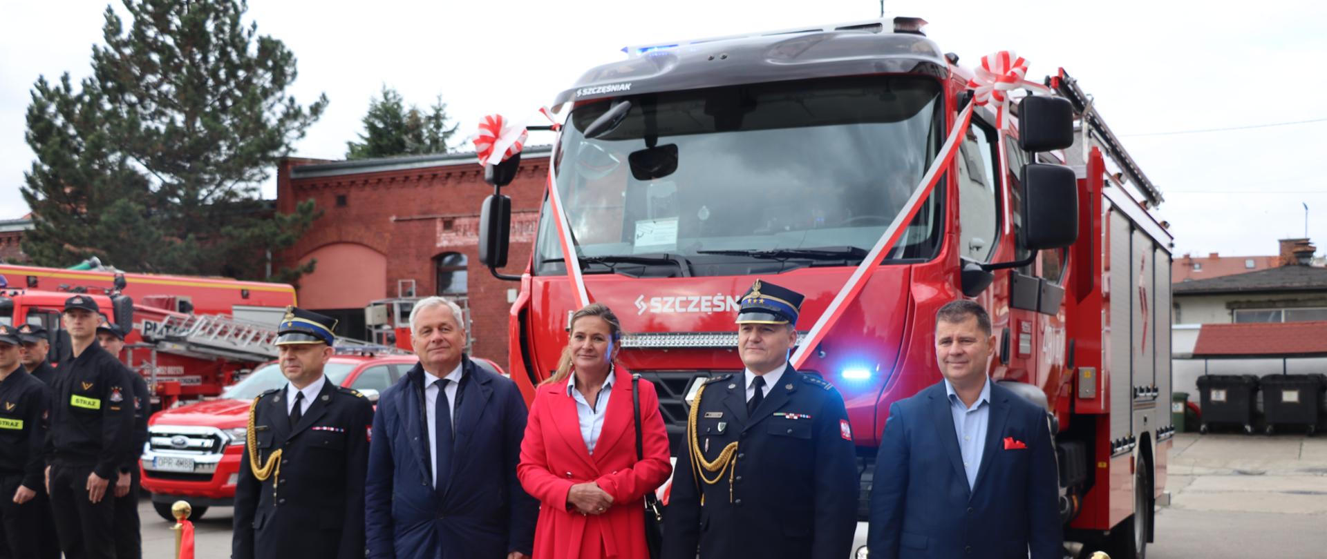 grupa ludzi stojąca przed wozem strażackim 