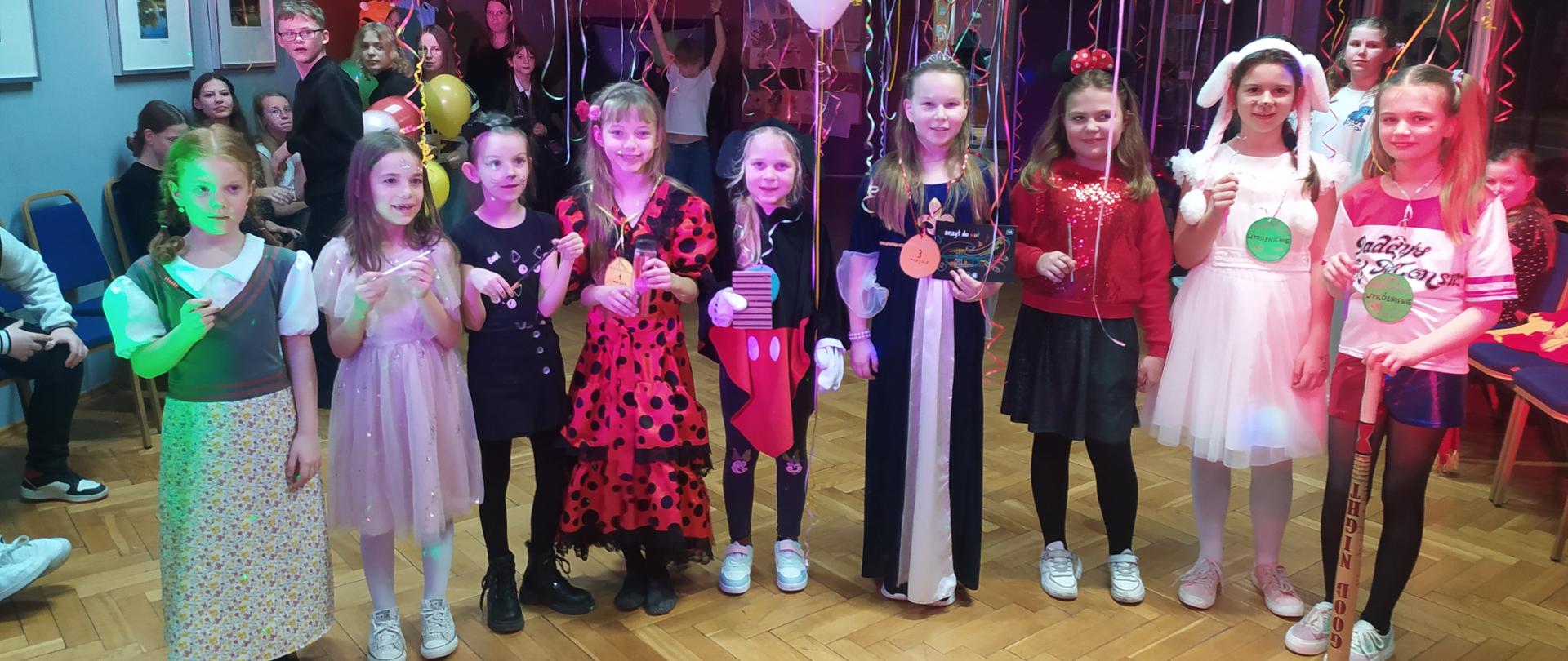 Uczniowie w strojach karnawałowych ustawieni w rzędzie. 