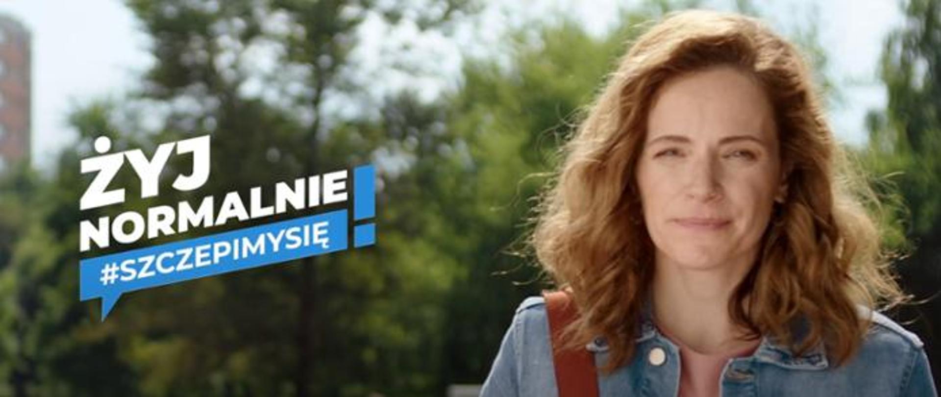 Na zdjęciu po prawej stronie widoczna jest kobieta. Po lewej stronie znajduje się napis ŻYJ NORMALNIE #SZCZEPIMYSIĘ! W tle widoczne jest niebo oraz drzewa.
