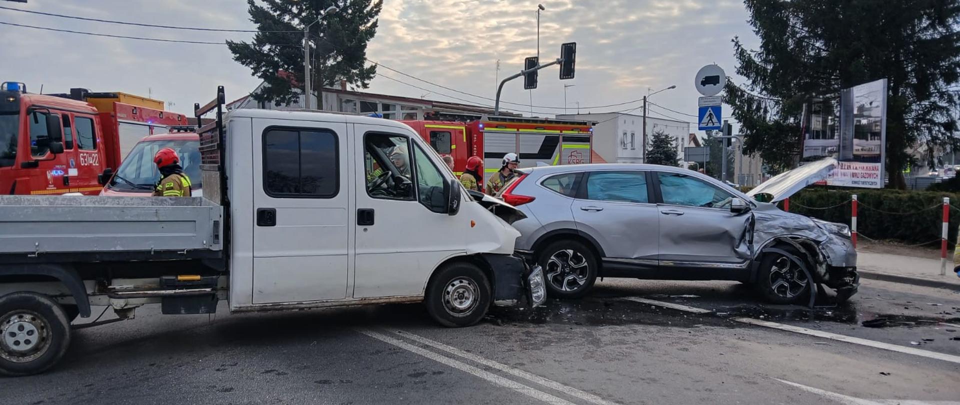 Na zdjęciu widać rozbite pojazdy oraz w tle pojazdy straży pożarnej 