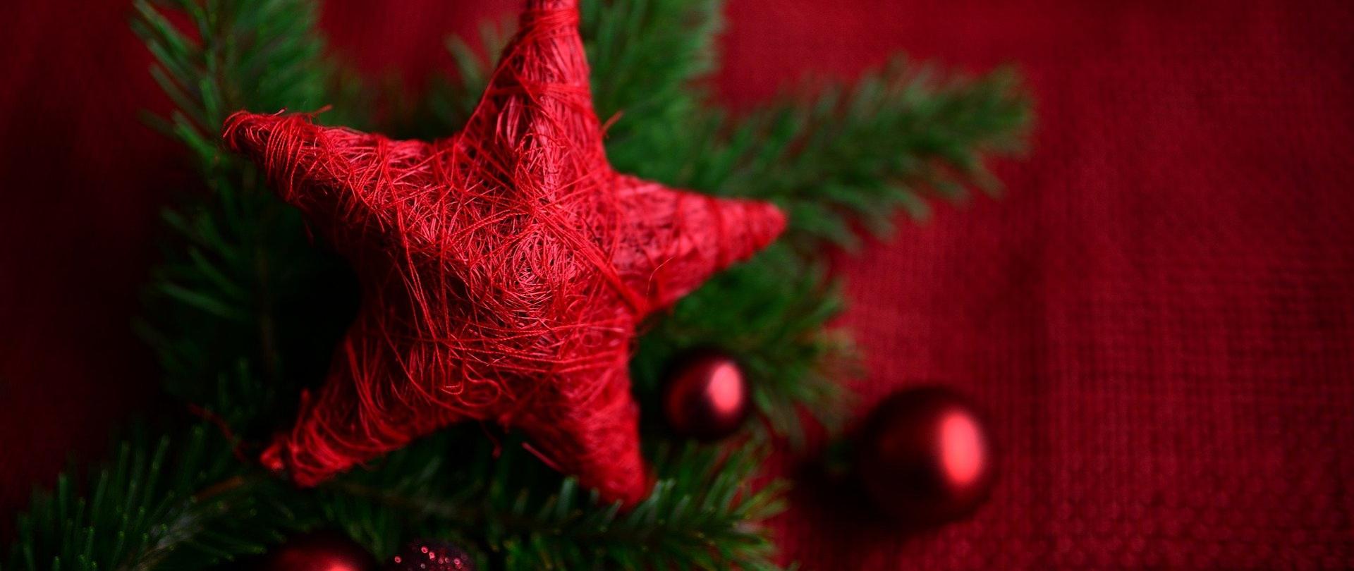 Czerwona gwiazda na zielonych iglastych gałązkach z czerwonymi bombkami