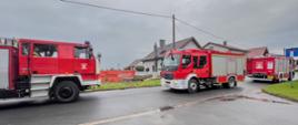 Na zdjęciu widać trzy pojazdy strażackie koloru czerwonego stojące w obrębie skrzyżowania.