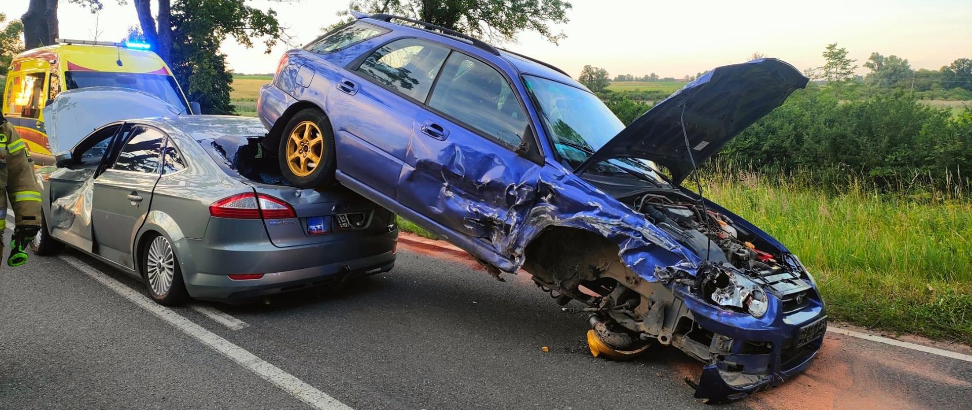 Zdjęcie przedstawia pojazdy uczestniczące w kolizji. Tylna oś subaru zatrzymała się na tylnej klapie osobowego forda