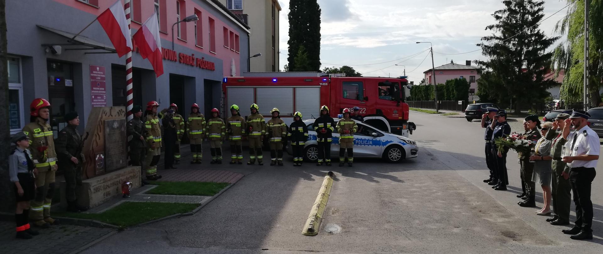 Zebrani przed pomnikiem strażackim składają wiązanki i zapalają znicze