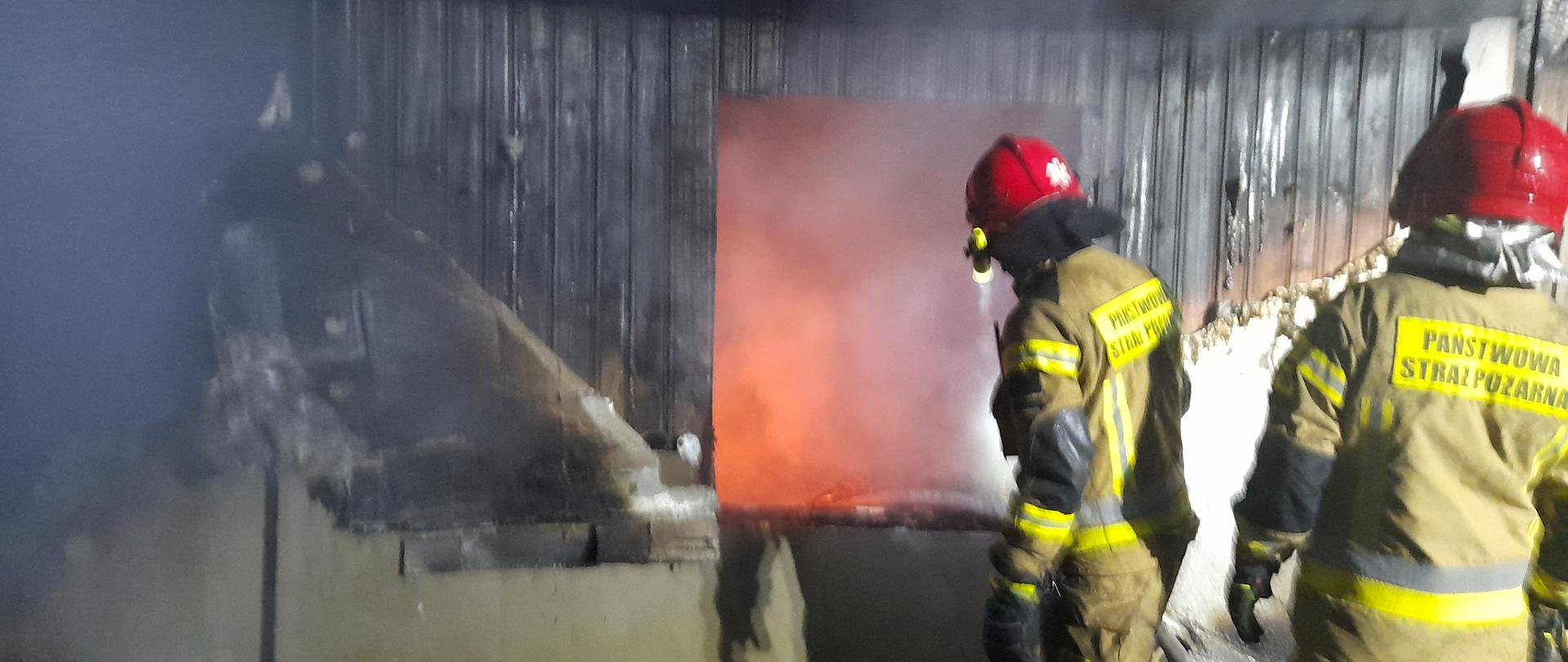 Zdjęcie obrazuje strażaków przy palącym się budynku