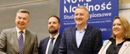Pod niebieskim banerem z napisem Nowa Mobilność stoi minister Wieczorek, dwóch mężczyzn w garniturach i kobieta w jasnej marynarce, jeden z mężczyzn trzyma w ręku dyplom.