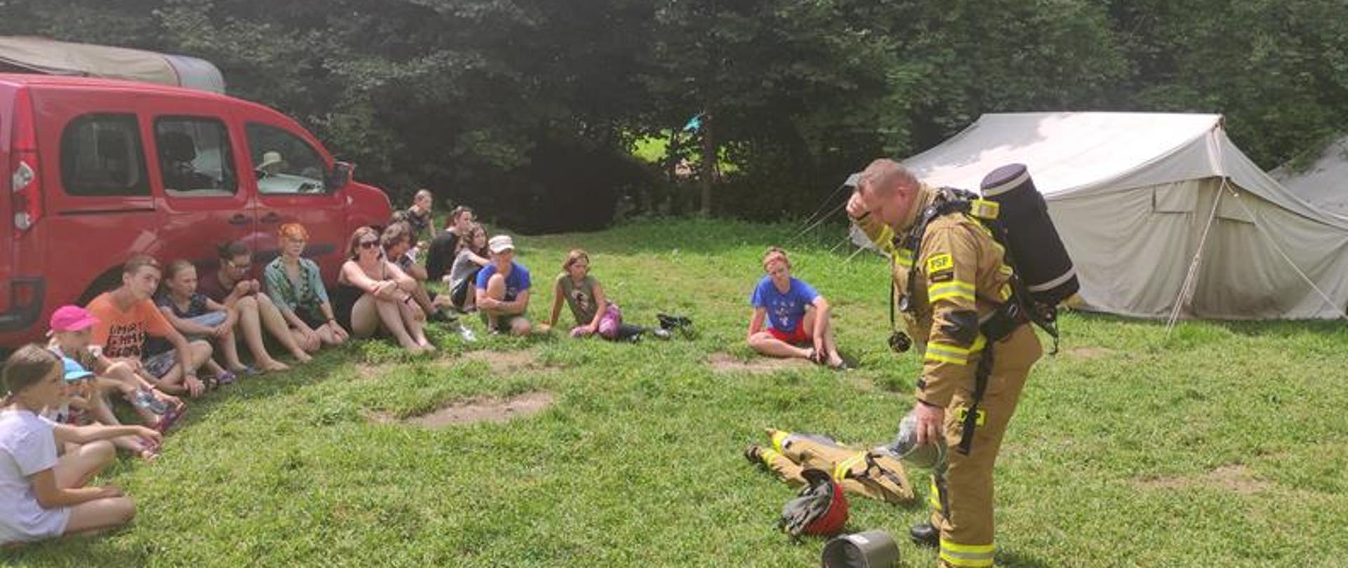 Strażak pokazuje sprzęt jaki zakłada podczas gaszenia pożaru w pomieszczeniach zadymionych.
