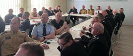 Zdjęcie przedstawia strażaków OSP i PSP podczas narady oglądających prezentację