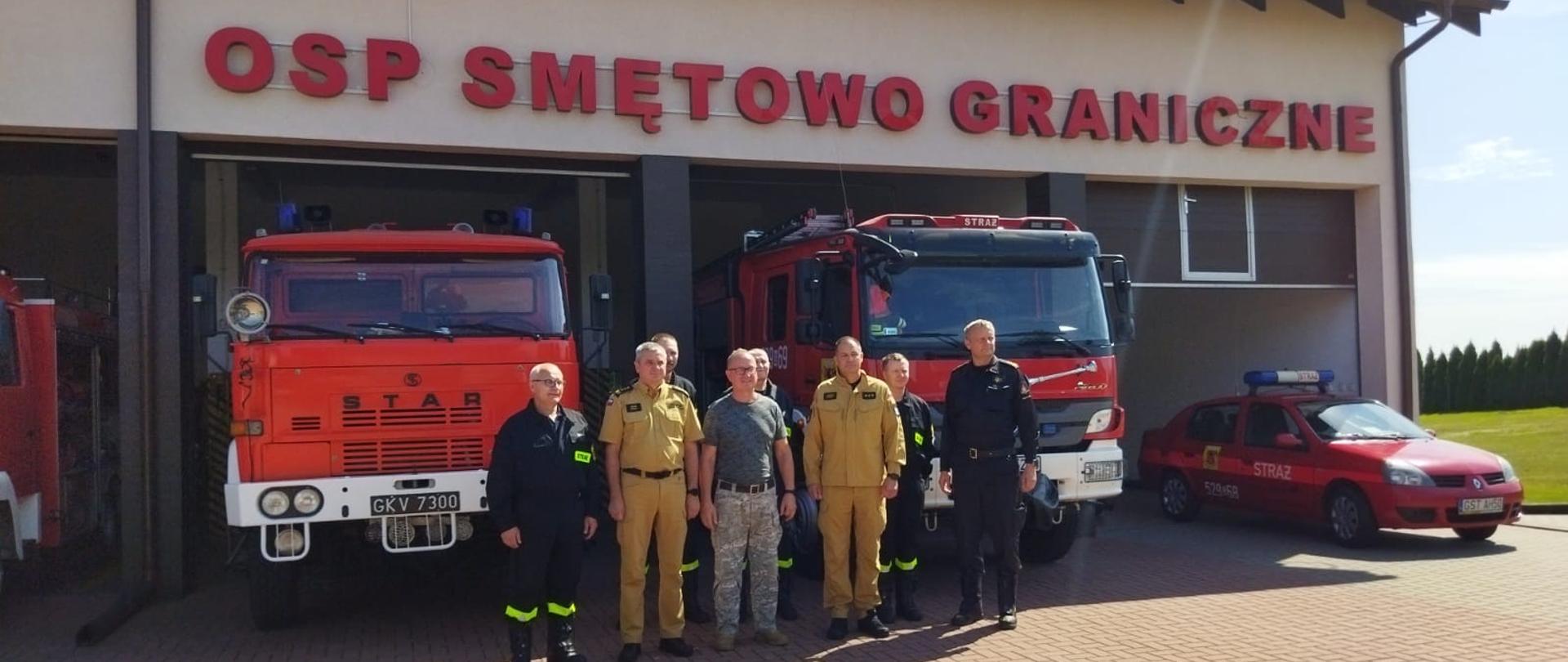 Zdjęcie przedstawia wizytujących wraz ze strażakami OSP na tle jednostki