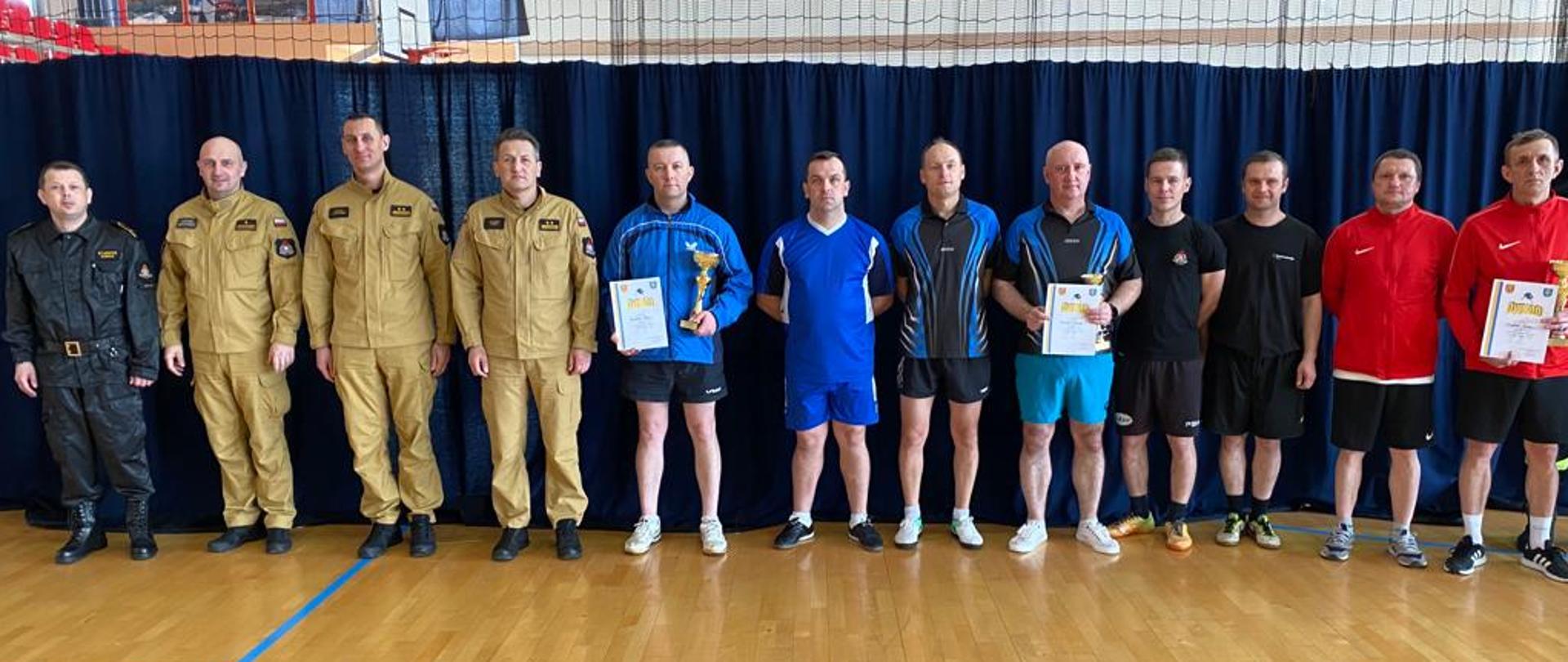Zdjęcie przedstawia członków zwycięskich drużyn w turnieju wraz z Komendantem Miejskim PSP w Kielcach i jego zastępcą