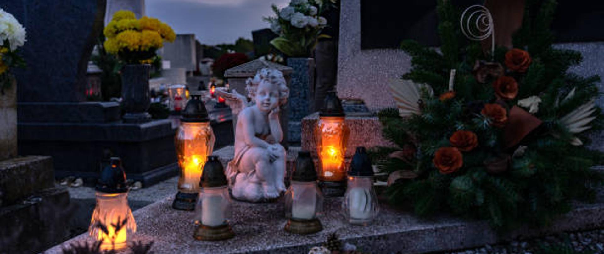 Znicza na cmentarzu w dzień wszystkich świętych z figurą anioła.