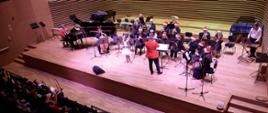 Grający Big-Band, śpiewająca uczennica i dyrygent na scenie sali koncertowej PSM