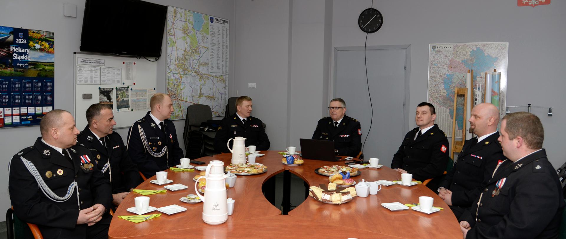 Na zdjęciu Zastępca Śląskiego Komendanta Wojewódzkiego PSP omawia założenia Ustawy o Ochotniczych Strażach Pożarnych. Uczestnicy spotkania siedzą wokół stołu konferencyjnego w sali sztabowej. Widoczni są druhowie jednostek OSP oraz funkcjonariusze PSP.