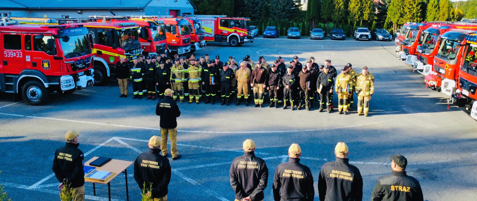 Odprawa i szkolenie BHP strazacy na zbiórcze w tle samochody