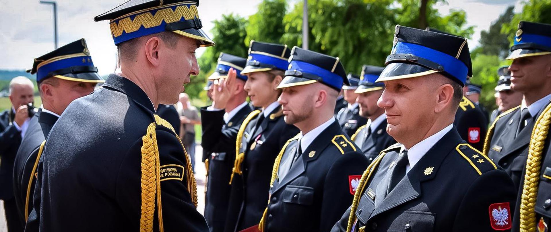 Zdjęcie zrobione podczas uroczystego apelu z okazji Wojewódzkich Obchodów Dnia Strażaka. Na zdjęciu uczestniczy uroczystości, wśród nich oficerowie Pa ństwowej Straży Pożarnej